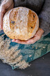 © Ina - Woman hands holding fresh homemade bread loaf. Cozy rustic scene with natural textures. Concept of comfort food, cozy home, handmade baking and slow living