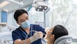 © Future Vision - Leaning male dentist wearing navy scrubs treating patient in clinic, with drill and dental light