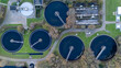 © MSG919 - Top down aerial view of a wastewater treatment plant with circular clarifier tanks, water basins, service roads and technical infrastructure. Industrial water management facility seen from above.