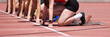 © pavel1964 - Group of female track athletes on starting blocks.Hands on the starting line. Athletes at the sprint start line in track and field