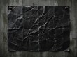 © Popy - Black crumpled poster paper pinned to rough dark concrete wall.