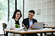 © Witoon - Two business professionals collaborating on a laptop in a modern office, discussing ideas and reviewing projects, showcasing teamwork, productivity, and workplace communication.