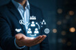 © muhammad - Businessman holding digital HR management and networking icons. Staff recruitment, global leadership, and corporate strategy concept.