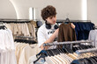 © Светлана Мищенко - Young shopper making buying decision in fashion retail store. Teenage consumer choosing apparel in clothing store