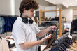 © Светлана Мищенко - Teenage boy examining price tag on T-shirt while shopping in clothing store. Young consumer comparing apparel and making purchase decision in retail environment.