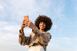 © Ezequiel Gimenez/Stocksy - Happy woman recording video on smartphone outdoors