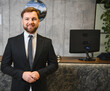 © Serhii - Male hotel receptionist welcoming guests at reception desk