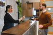 © Serhii - Receptionist assisting guest with hotel key card check in