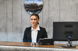 © Serhii - Female receptionist working at hotel front desk