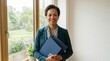 © spyrakot - Confident community mediator holding folders by office window