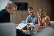 © Drazen - Smiling man and his wife analyzing financial offer while being on meeting with bank manager in office.