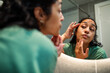 © Marko Geber - Young woman checking skin in bathroom mirror