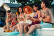 © Zamrznuti tonovi - Diverse friends laughing and enjoying a summer pool party with drinks and snacks, relaxing outdoors