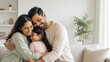 © ArtFocus Studio - Happy Indian family of three embracing at home, smiling parents hugging daughter in living room