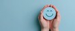© Arfa_Media - Hands holding a blue card with a smiley face icon for positive customer feedback