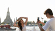 © blueringmedia - Man Taking Photo of Woman by Wat Arun Temple in Bangkok