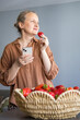 © Ina - Woman holding smartphone and eating fresh strawberry while relaxing at home. Healthy snack, digital lifestyle, online communication and leisure time in comfortable indoor environment.