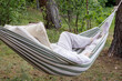 © Ina - Woman resting in striped hammock between trees during countryside getaway. Outdoor relaxation, leisure activity and peaceful recreation surrounded by natural landscape.