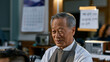 © Tania - Older Korean man in a barbershop apron clips a young customer's hair while speaking animatedly, traditional Korean calendar on the wall, handwritten price list in two languages taped to the mirror,