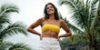 © Aleksei Solovev - Athletic brunette woman with tattoo on her shoulder wearing a yellow strapless top and white pants posing confidently in front of palm trees and a cloudy sky.