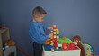 © Krakenimages.com - Hispanic boy carefully stacking colorful plastic blocks with hands into a tall tower on a play table in building; quiet concentration.