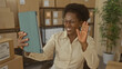 © Krakenimages.com - Business owner woman holding tablet waves hand amid stacked shipping boxes in packing building; entrepreneurial optimism small business.