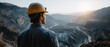 © Kingdola - Miner's Perspective: A lone miner in a hard hat surveys a vast open-pit mine at sunrise, his gaze fixed on the expansive industrial landscape stretching out before him.