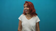© Krakenimages.com - Woman smiling with visible face and red hair, wearing a white t shirt against a teal studio wall; joy confidence openness.