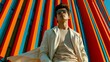 © LaVisionique - Bold stripes blaze behind a stylish man. He wears sunglasses, a light coat, and a soft shirt. His gaze rises confidently, hinting at cool self-assurance. Sunlit, bold colors contrast his calm