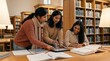 © mashimara - Three students working together in a library on academic projects