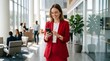 © Ataur_1344 - Professional woman checking smartphone in modern office lobby with natural light