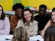 © Breezze - Smiling female teacher engage in a candid open discussion with diverse students in a bright, sunny classroom for education and mentorship content