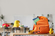 © Pixel-Shot - Orange backpack with school supplies on desk in classroom