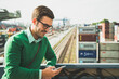 © Westend61 - Man at freight yard looking at cell phone