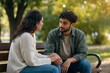 © Cahya - Young couple holding hands on a park bench while having a serious talk, reflecting deep emotional support, trust, and relationship communication