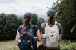 © bubutu - Back View of Two Teenage Girls with Backpacks Standing Together at an Outdoor Viewpoint and Looking at a Beautiful Mountain Forest Landscape