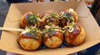 © StocksJust4You - Freshly cooked Japanese takoyaki drizzled with savory sauces inside takeaway box, steaming street food