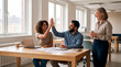 © Rendara Studio - Diverse team celebrating work achievement with high five in bright modern office space
