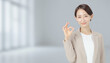 © noonekoon - Successful businesswoman gesturing ok with blurry office window background 明るいオフィスの窓を背景にOKサインを出す上品なビジネス女性