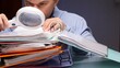 © Aliaksandr - Man holding a magnifying glass, intently reviewing financial documents and binders, symbolizing detailed investigation, deep analysis, and thorough research of important information