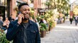 © Eve - Happy young black man talking on smartphone smiling on city street handsome african american guy in denim jacket communicating outdoor