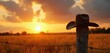 © Vadym - Cowboy hat rests on weathered fence post. Golden hour sunset bathes dry grass field in warm light. Barbed wire stretches across rural landscape. Serene western scene.