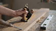 © Ali - A woodworker using a hand plane on a wooden board in a workshop