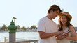 © blueringmedia - Smiling Asian Couple Using Smartphone by Riverside at Sunset in Bangkok