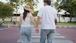 © blueringmedia - Young Asian Couple Holding Hands While Walking Across a City Crosswalk