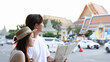 © blueringmedia - Young Asian couple consulting a map on a street near a temple