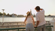 © blueringmedia - Young Couple Looking at Riverside Temple During Golden Hour Sunset