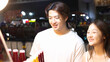© blueringmedia - Young Asian Couple Smiling While Choosing Drinks at Night Market