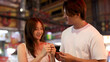 © blueringmedia - Young Asian Couple Sharing Roasted Chestnuts at a Vibrant Night Market