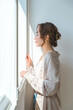 © buritora - A stylish woman standing by the living room window.